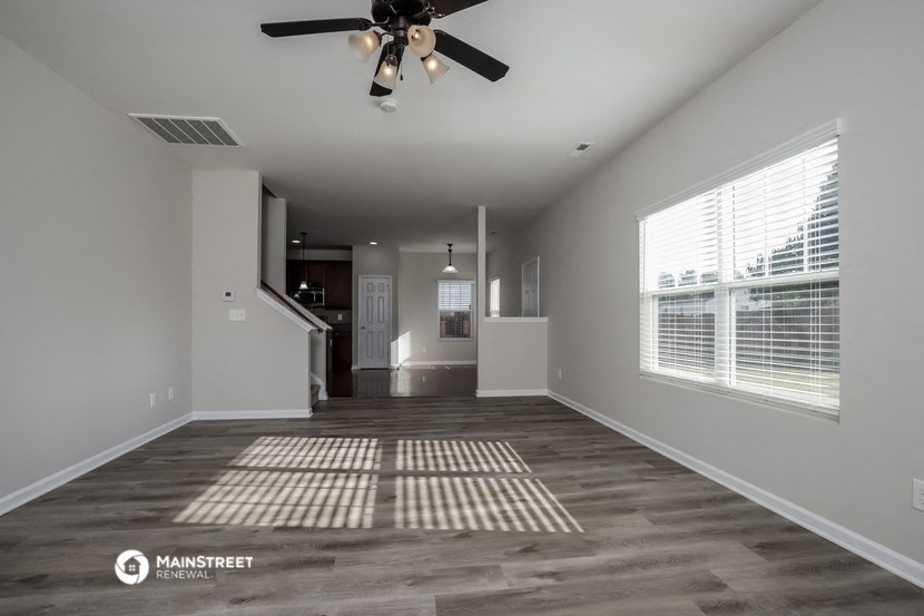 an empty living room with a ceiling fan and a window