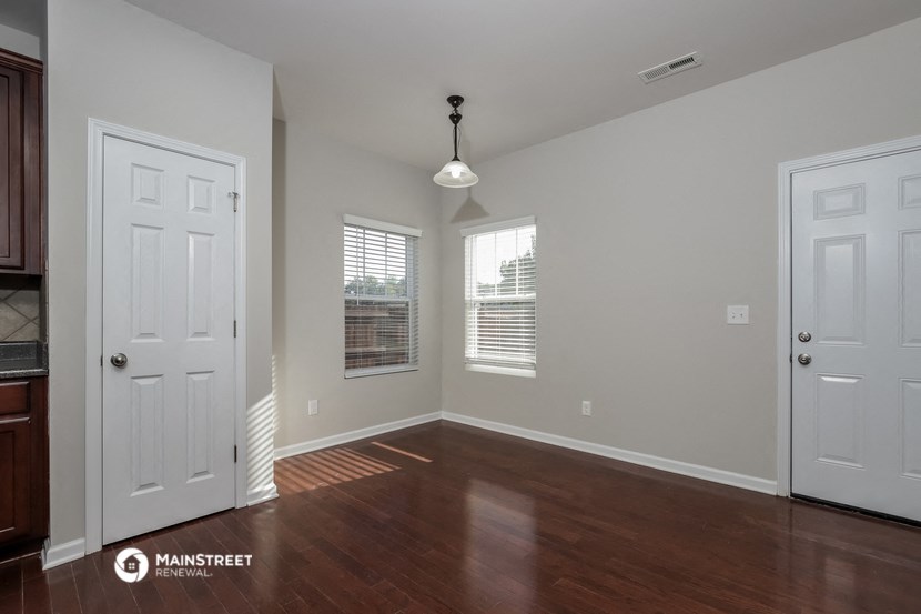 an empty living room with wood floors and a white door
