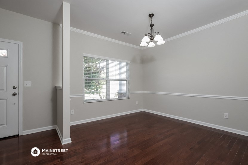 the spacious living room with hardwood flooring and a window