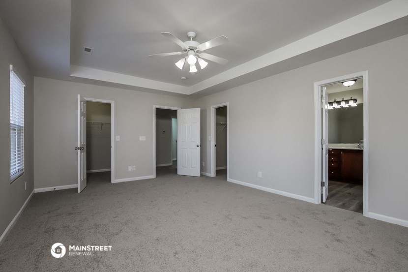 an empty living room with a ceiling fan