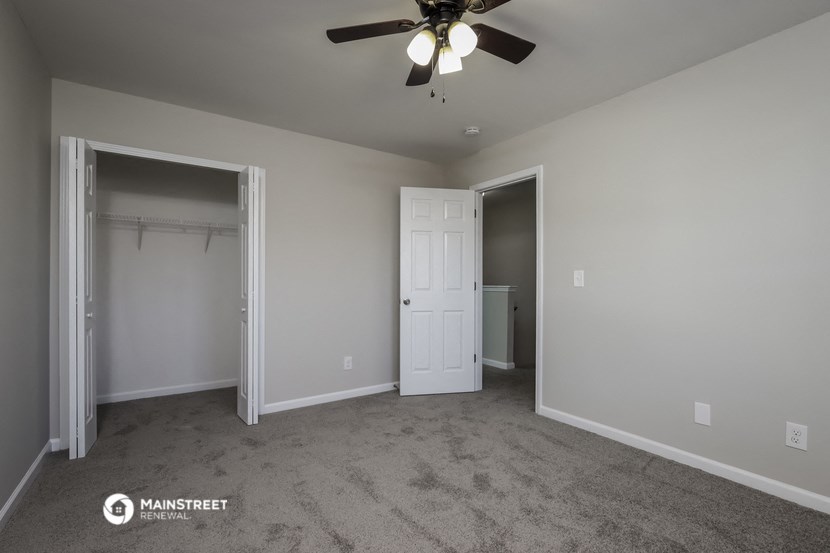 a bedroom with a ceiling fan and a closet