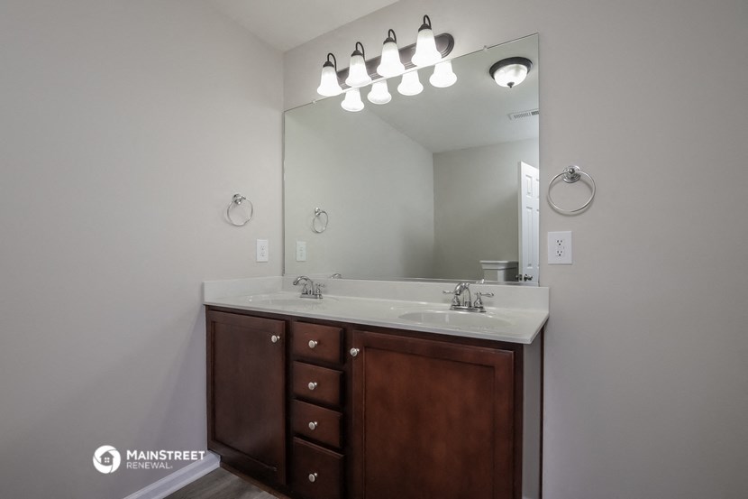 a bathroom with a sink and a mirror and a wooden cabinet
