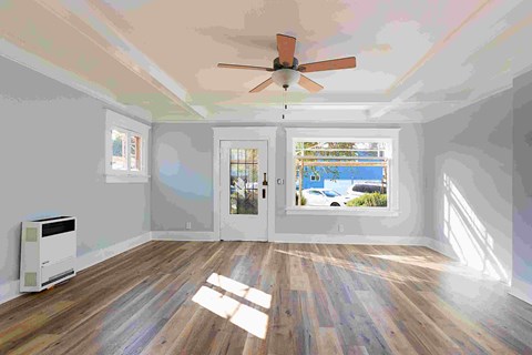 an empty living room with white walls and a ceiling fan