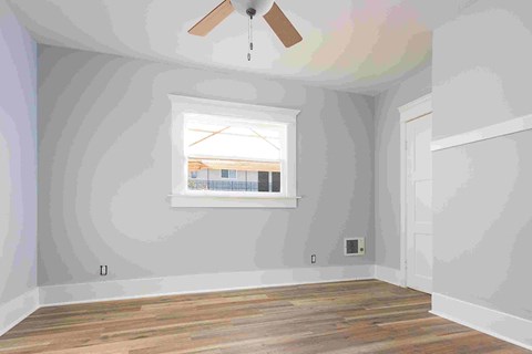an empty room with a window and a ceiling fan