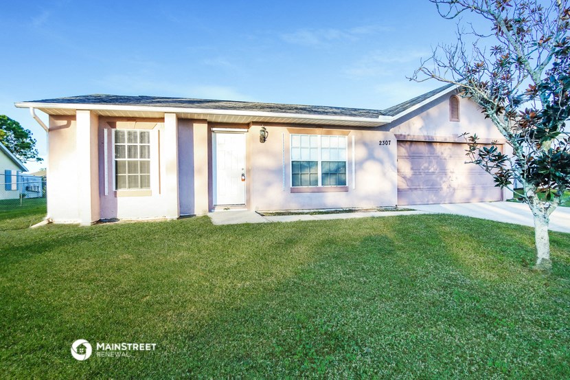 a small white house with a lawn and a tree