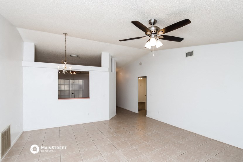 an empty living room with a ceiling fan and a tile floor