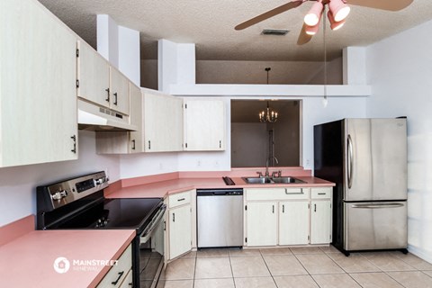 a kitchen with white cabinets and pink counter tops and a sink