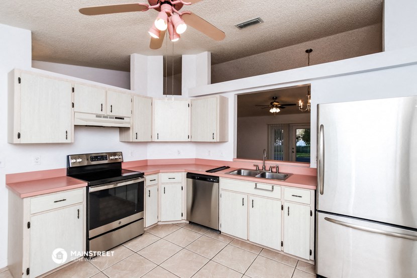 a kitchen with white cabinets and a pink counter top