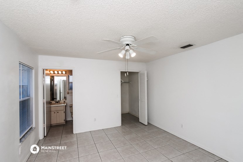 a living room with a ceiling fan and a door to a bathroom