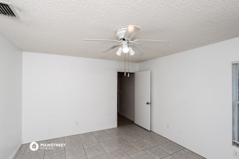 the living room of an apartment with a ceiling fan