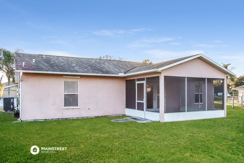 a small pink house with a porch and a lawn
