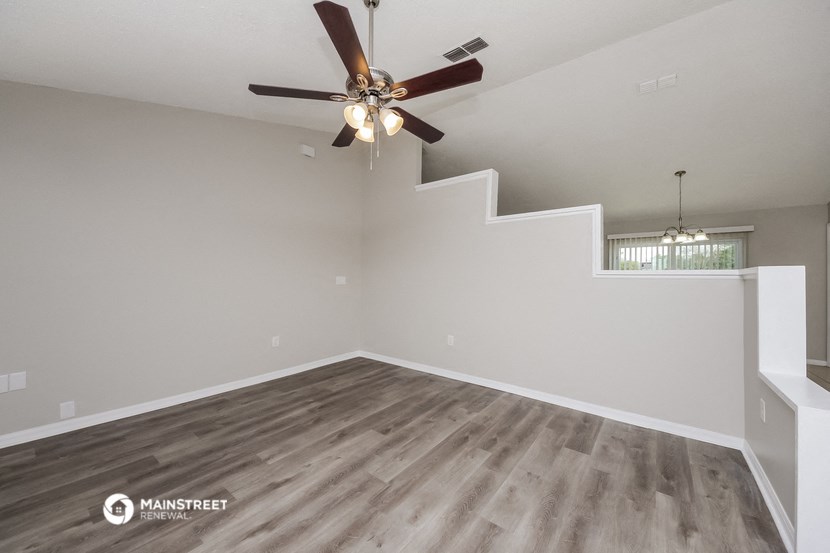 the spacious living room with stairs and a ceiling fan