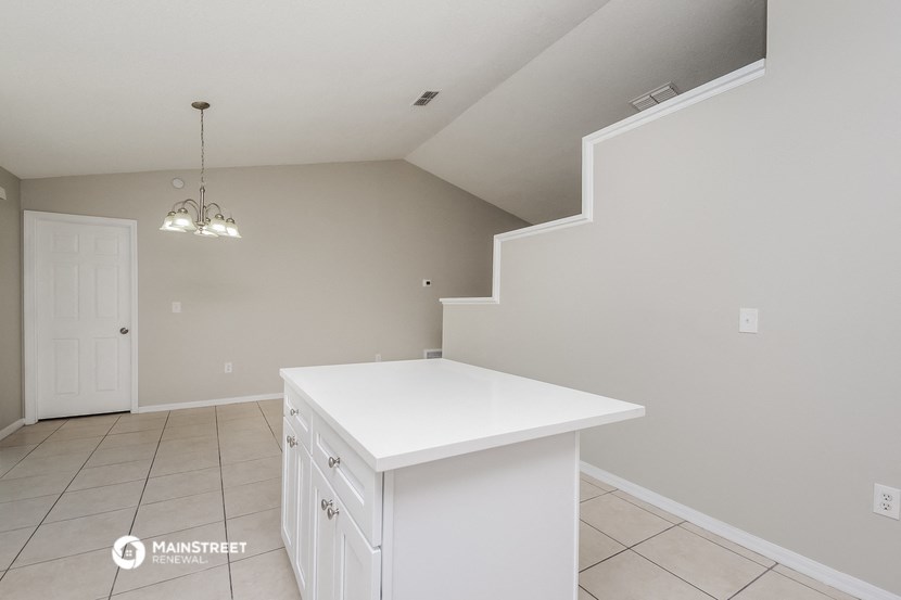 a white kitchen with a white counter top and a staircase
