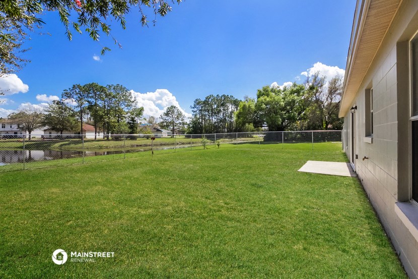 the backyard of a house with a tennis court and a fence