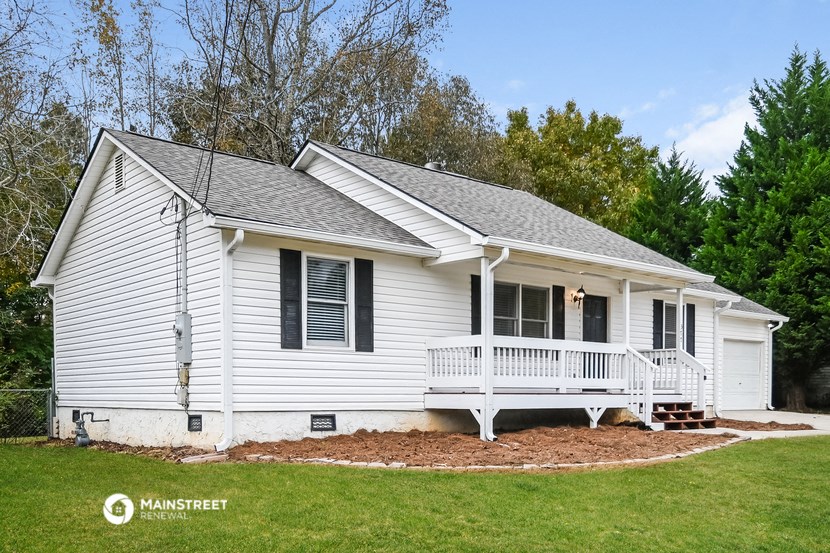 a white house with a porch and a green lawn