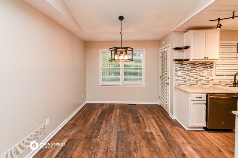 the kitchen and dining room of a house with wood flooring and a window