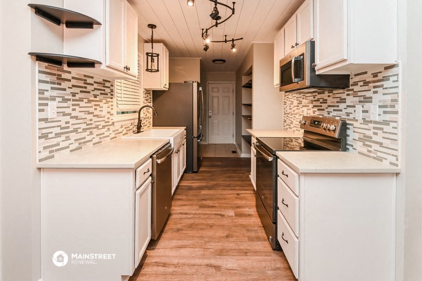 a kitchen with white cabinets and a wood floor
