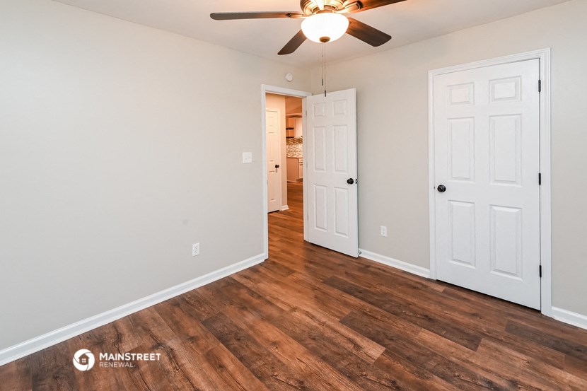 the living room of an apartment with wood flooring and a ceiling fan