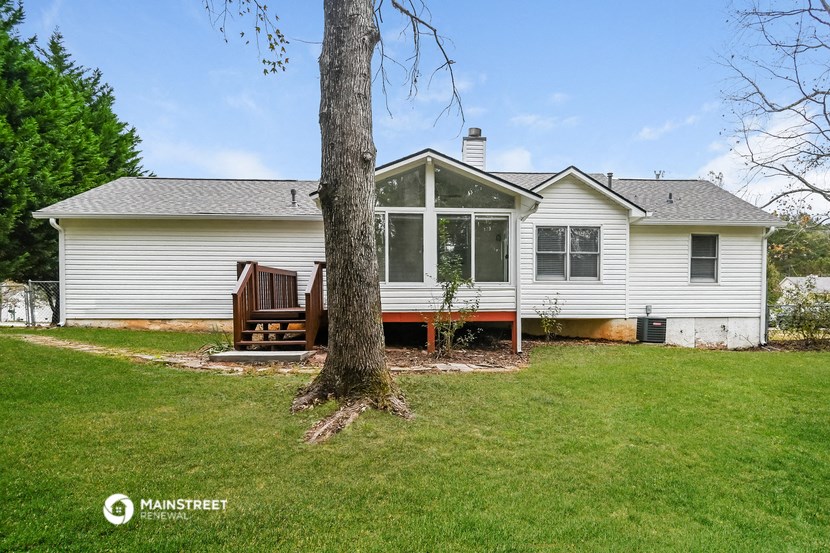 a white house with a deck and a tree in front of it