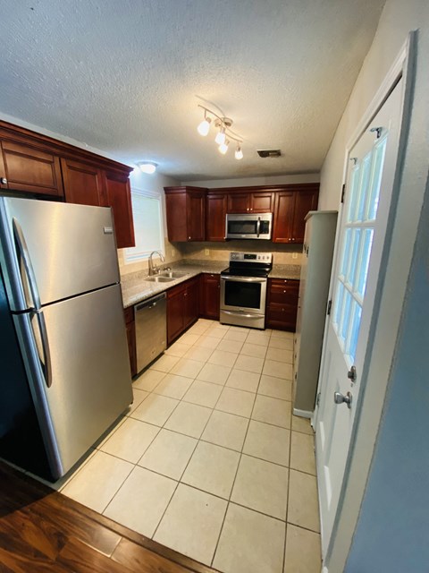 A kitchen with a refrigerator, microwave, oven, and sink.