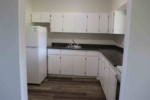 a kitchen with white cabinets and a sink and refrigerator