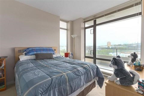 A bedroom with a large bed and a window overlooking a cityscape.