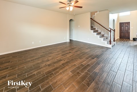 an empty living room with wood flooring and a staircase