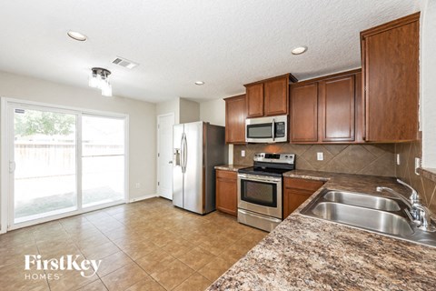 A kitchen with brown cabinets and a granite counter top.