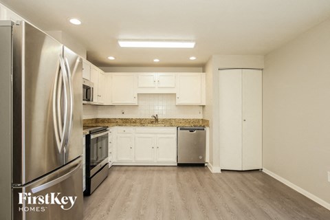 A kitchen with a stainless steel refrigerator and wooden floors.