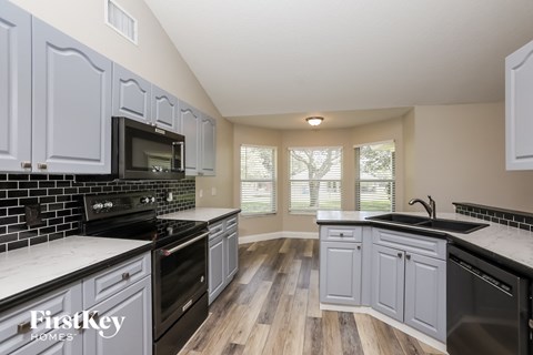 A kitchen with wooden floors and black appliances.