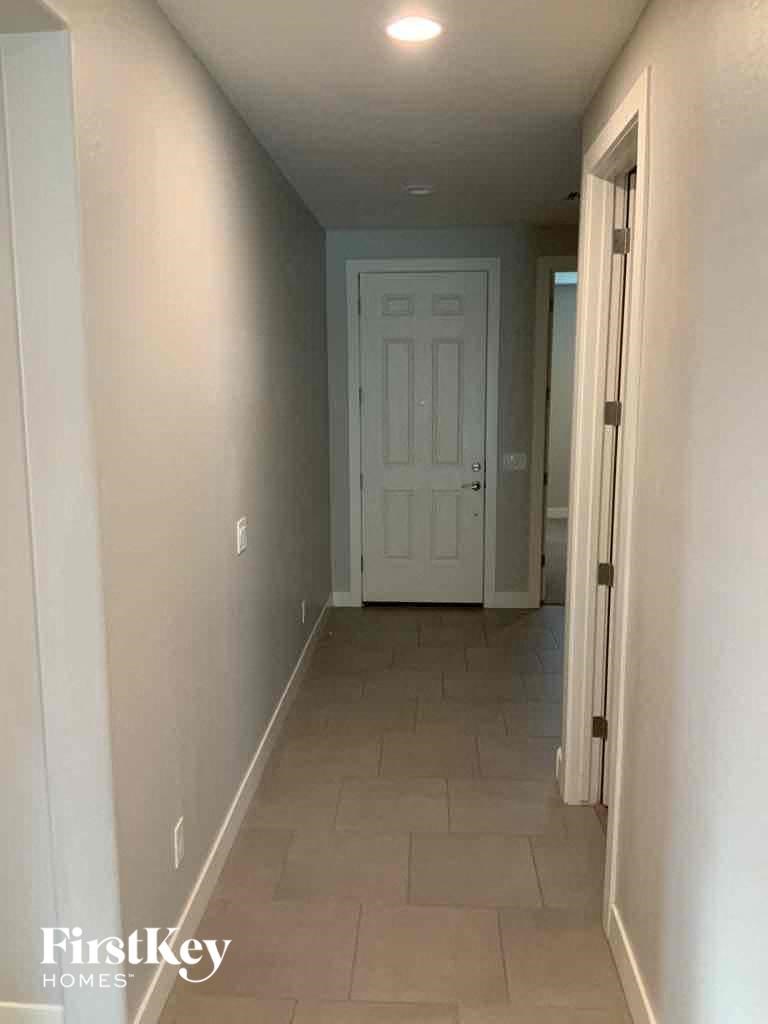 A hallway with a white door and tiled floor.