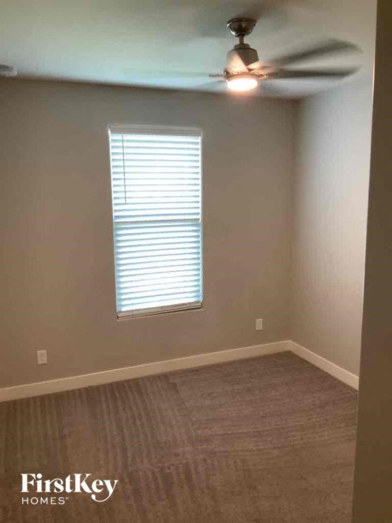 A room with a ceiling fan and a window with blinds.