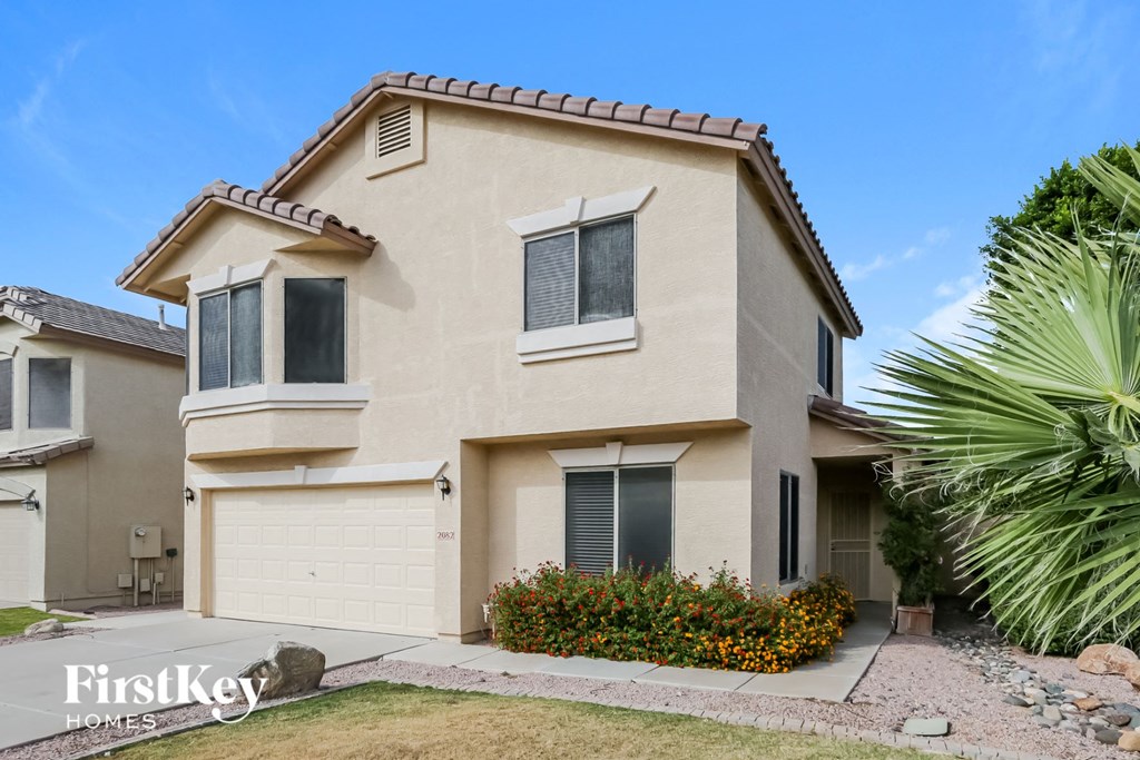 a beige house with a garage and a palm tree