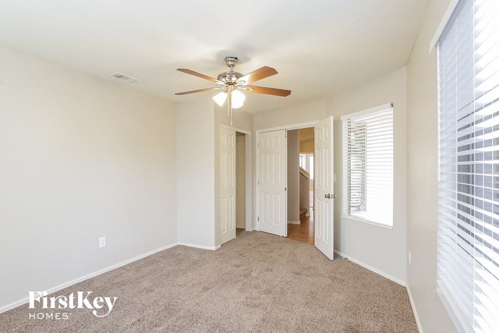 a living room with a ceiling fan and a door to a hallway