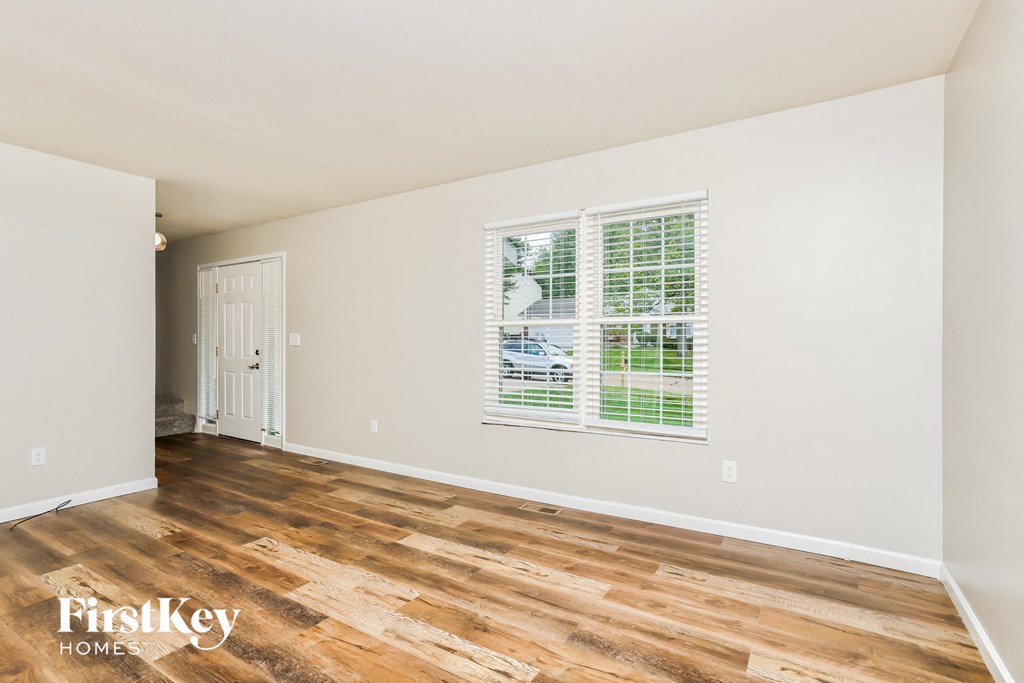a living room with wood floors and white walls and a door