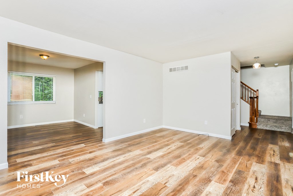 the living room and dining room with hardwood floors and white walls