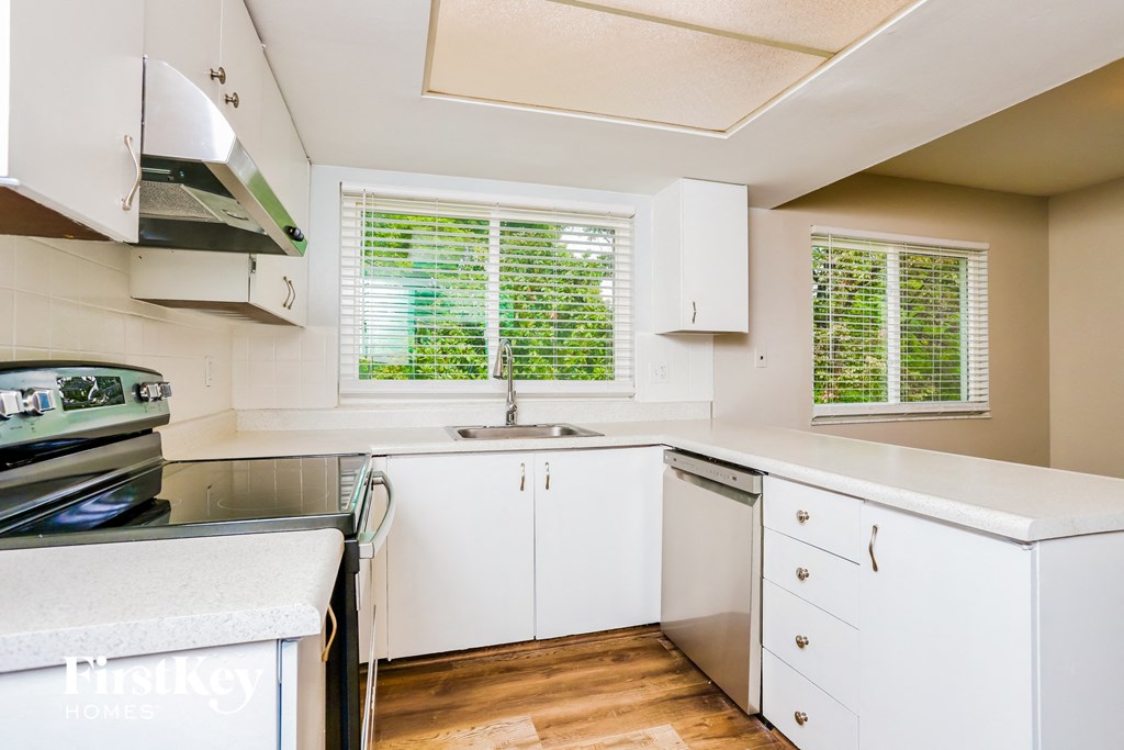 a kitchen with white cabinets and a sink and a window