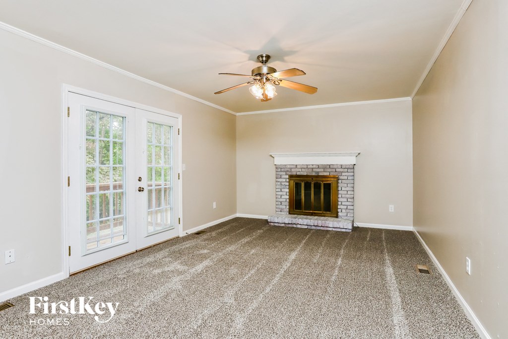 an empty living room with a fireplace and a ceiling fan