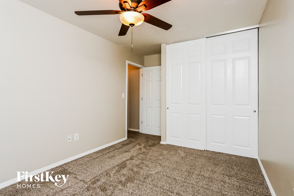 a bedroom with a ceiling fan and two closets