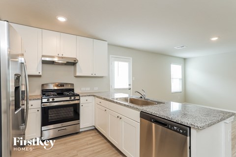 a kitchen with white cabinets and granite counter tops and stainless steel appliances