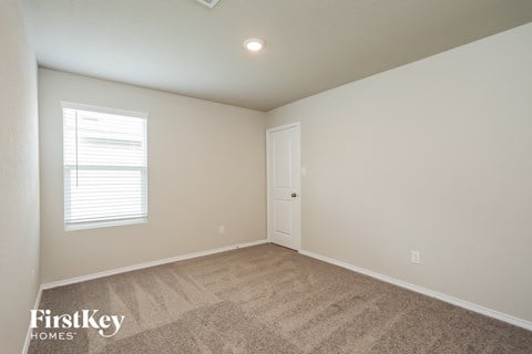 a bedroom with a carpeted floor and a white door and window