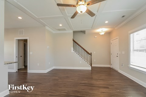 A spacious room with a wooden floor and a staircase.