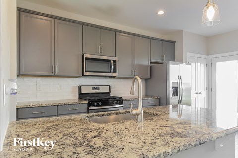 A kitchen with granite countertops and a stainless steel refrigerator.