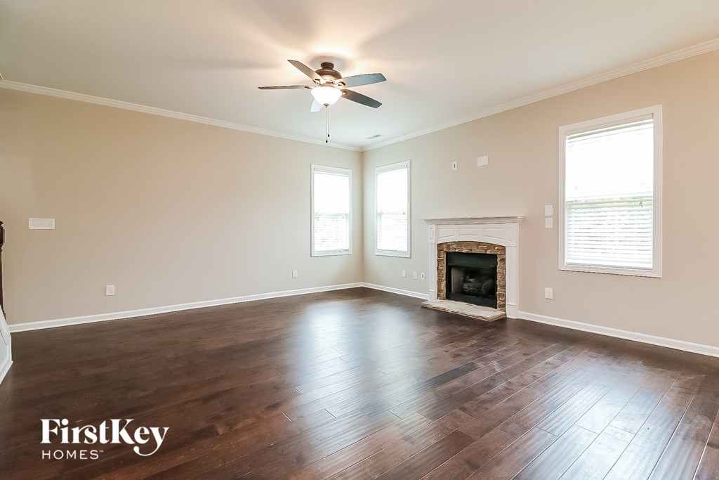 an empty living room with a ceiling fan and a fireplace
