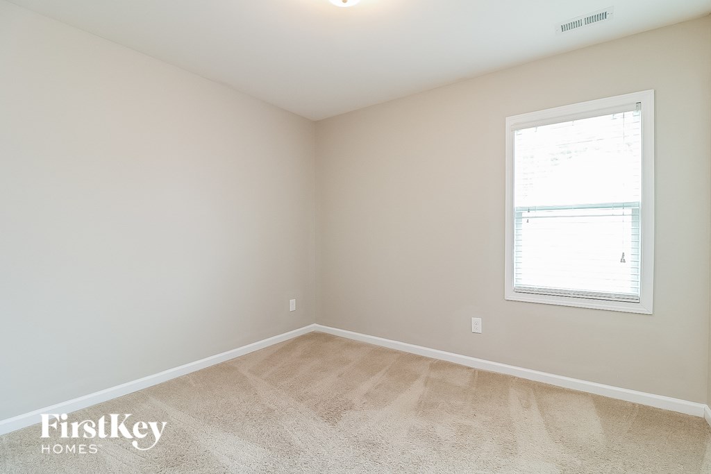 a bedroom with a window and a carpeted floor