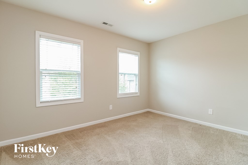 a spacious room with two windows and a carpeted floor