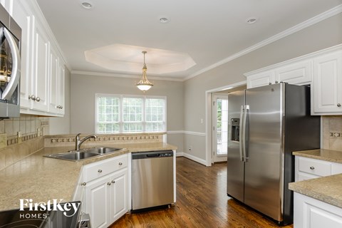 an updated kitchen with stainless steel appliances and white cabinets