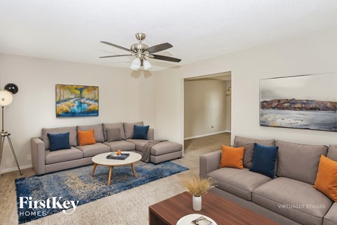 A living room with a grey couch and a blue rug.
