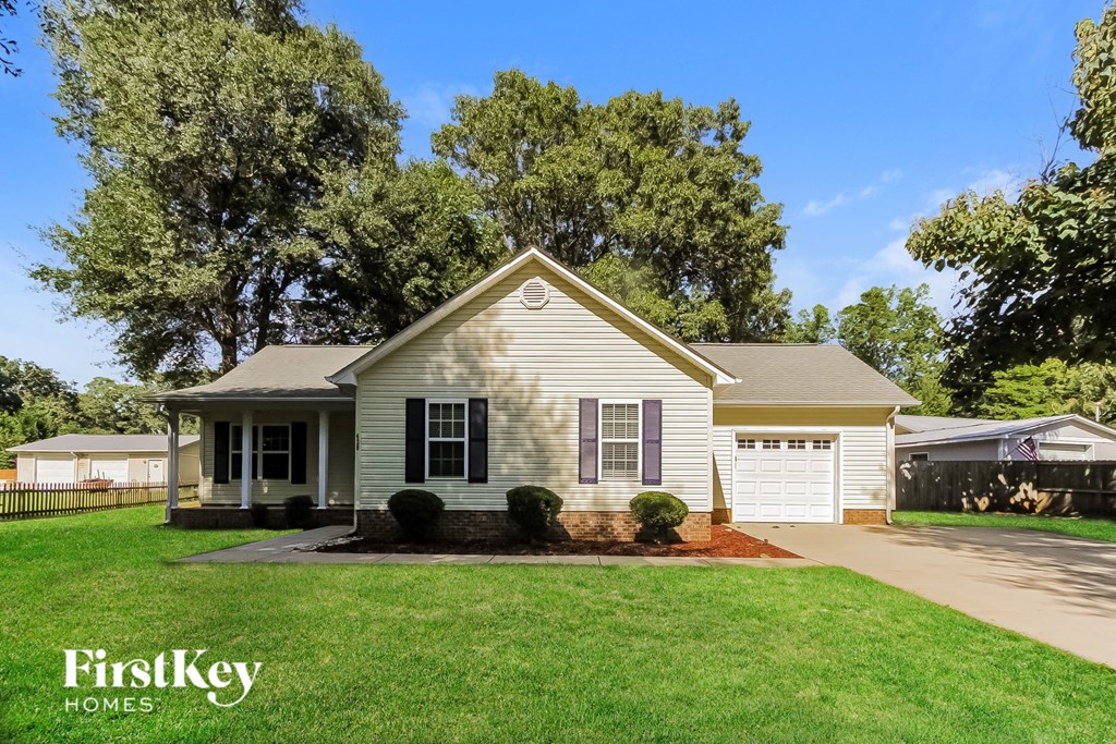 a small white house with a lawn and trees