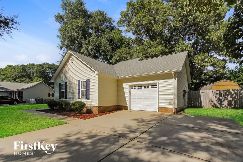 a yellow house with a white garage and a driveway